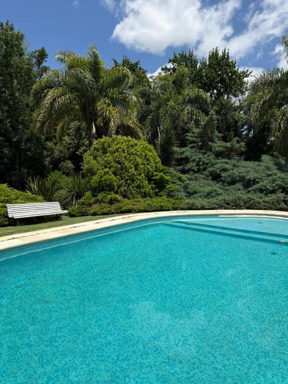 a blue swimming pool with a bench and trees at LPR EZE Airport in La Unión