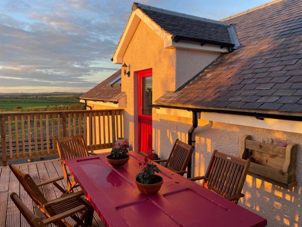 una mesa roja y sillas en el balcón en West Coast Whistlestop, en Ochiltree