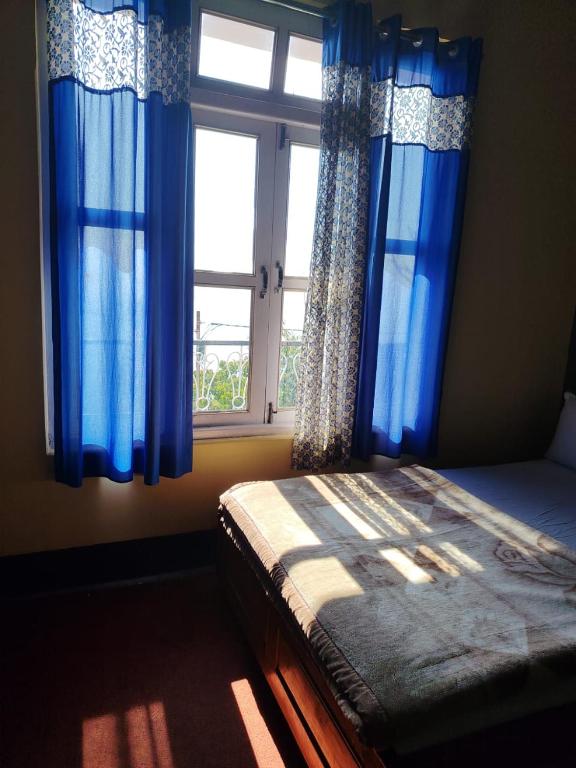 a bedroom with blue curtains and a bed with a window at Chander Pahar Retreat in Kalimpong