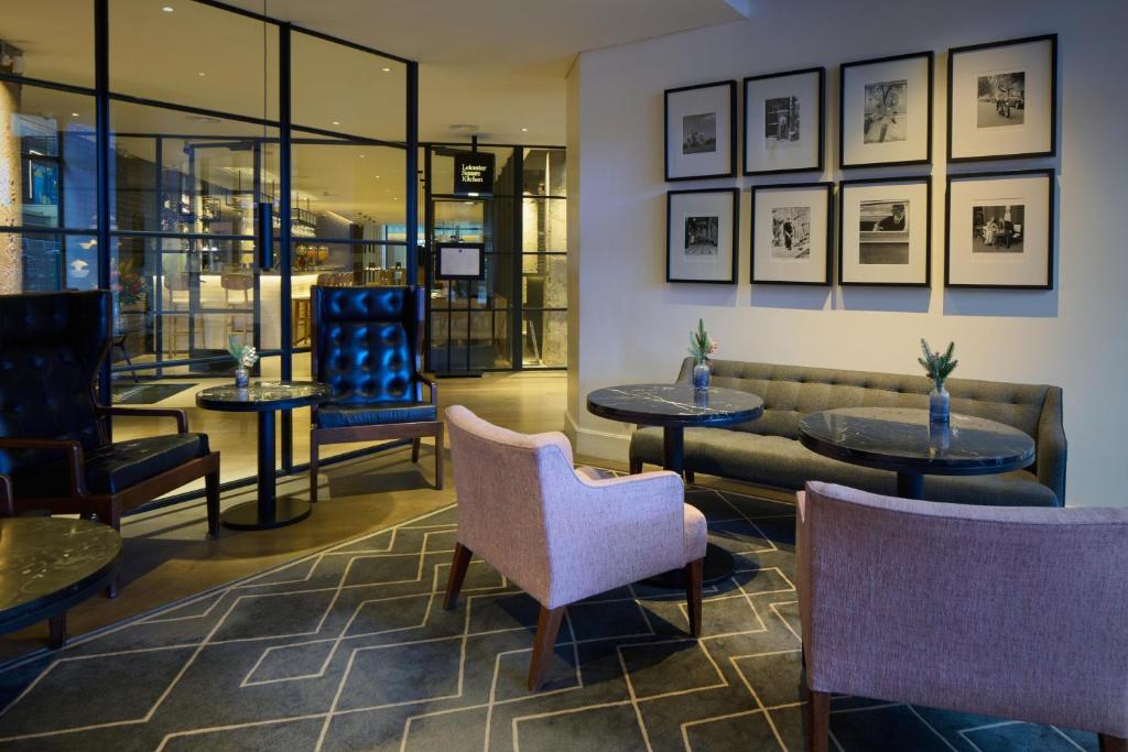 a lobby with tables and chairs and a couch at Radisson Blu Hotel, London Leicester Square in London