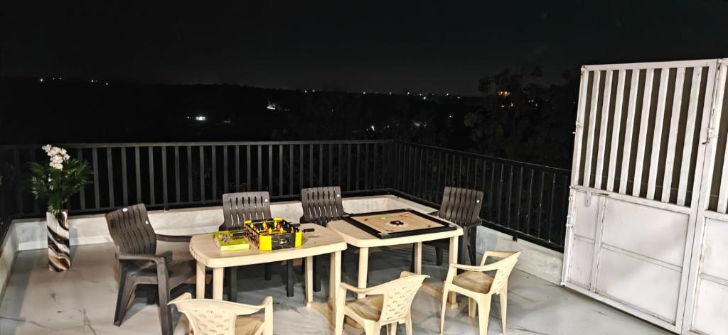 a table and chairs on a balcony at night at Staeg Dharashray Farm in Indore