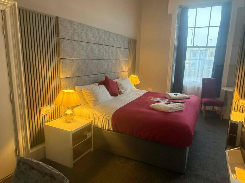 Un dormitorio con una cama grande con una manta roja. en The Jubilee Hotel West- with NEWLY REFURBISHED SPA FACILITIES - GAMESPIT - AND SMOKEHOUSE, en Weymouth