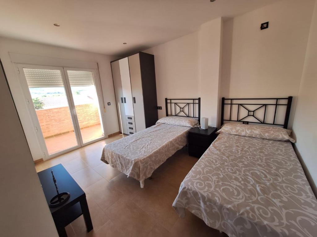 een slaapkamer met twee bedden en een groot raam bij Vista Noguera in Huéscar