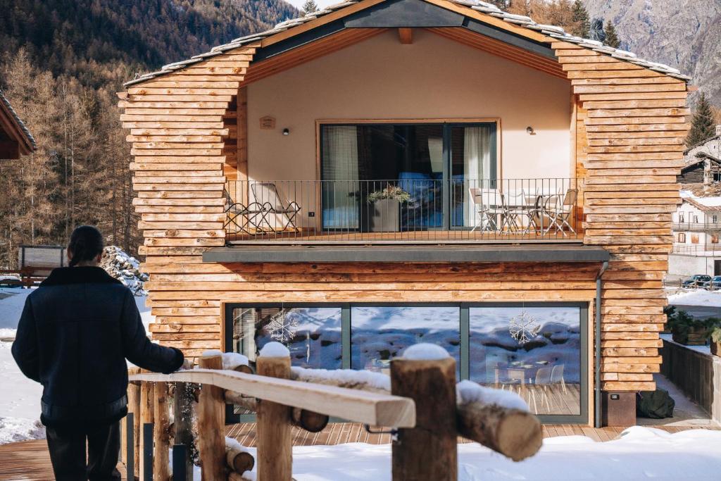 a person standing in front of a house in the snow at Les Chalets de Pierrot in Cogne