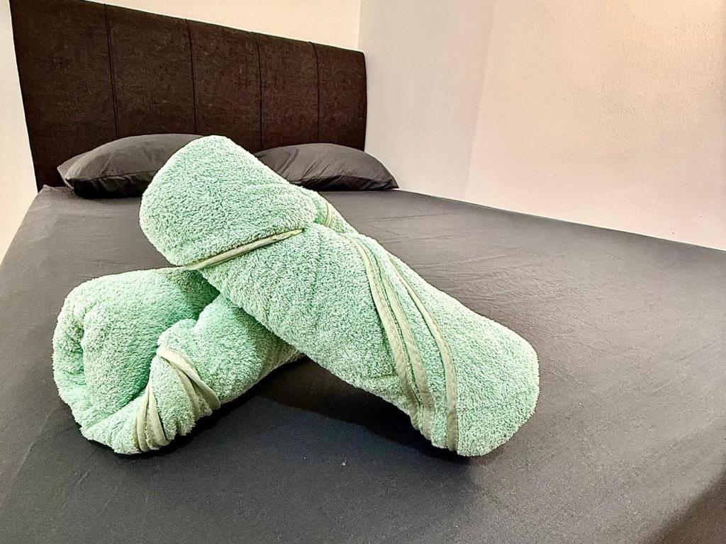 ein grünes Handtuch liegt auf einem Bett in der Unterkunft Luna Bliss Taman Koop AST Lobak Budget Hotel Room in Seremban