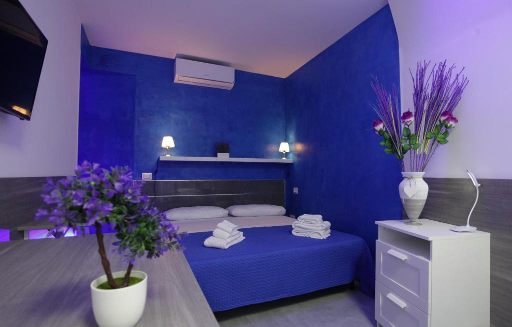 Un dormitorio azul con una cama y una mesa con flores en B&B Chiaia Relax, en Nápoles