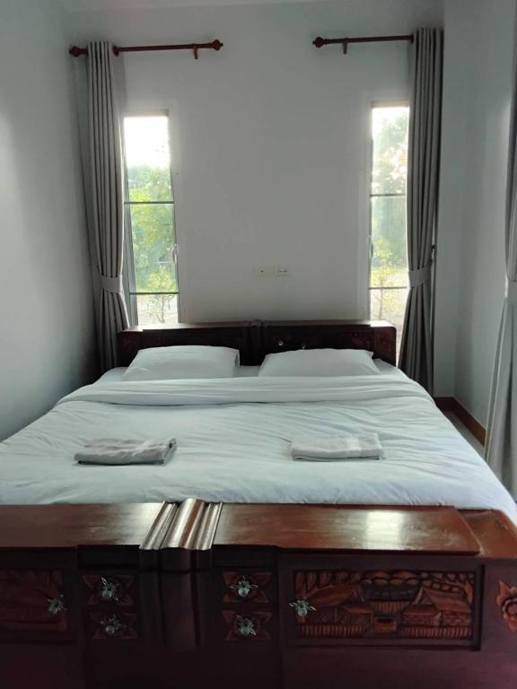 a bedroom with a large bed with two windows at Huan Janto Homestay - Nimmanaradee in Ban Sam Lang