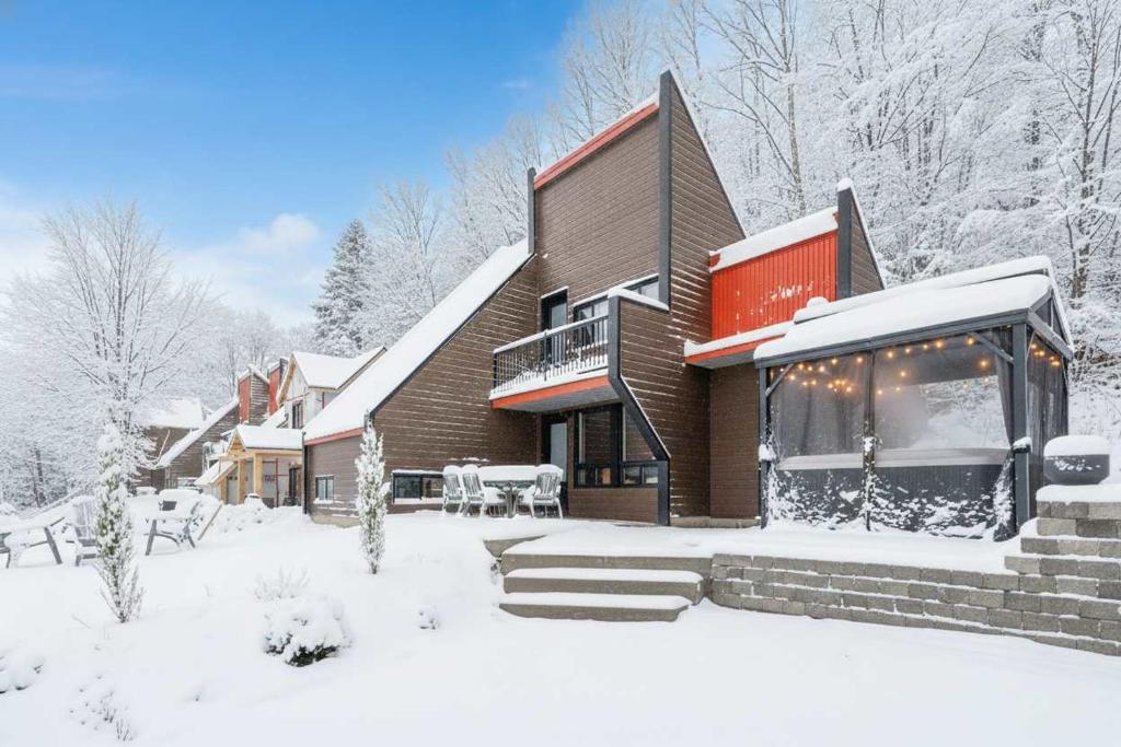 Spa & Nature view - Alpenglow في Sainte-Germaine-du-Lac-Etchemin: منزل فيه ثلج على الأرض أمامه