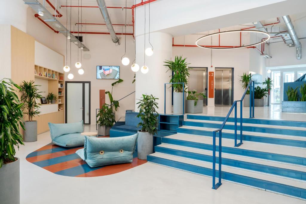 um hall de entrada de escritório com escadas azuis e plantas em vasos em aparto Milan Ripamonti em Milão