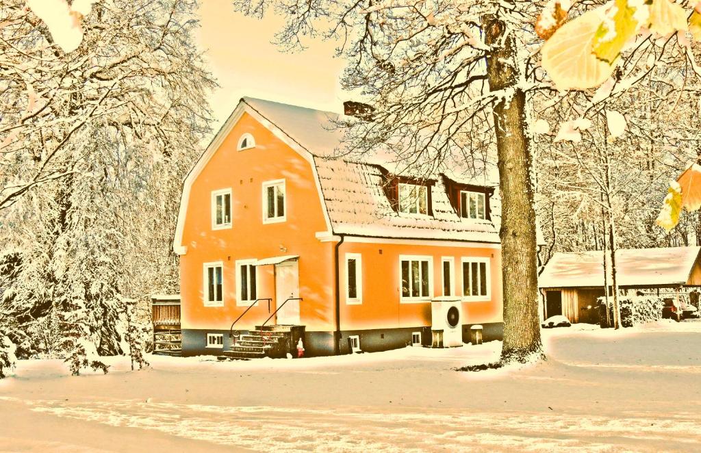an orange house in the snow with trees at Ekebo Guesthouse in Svalöv
