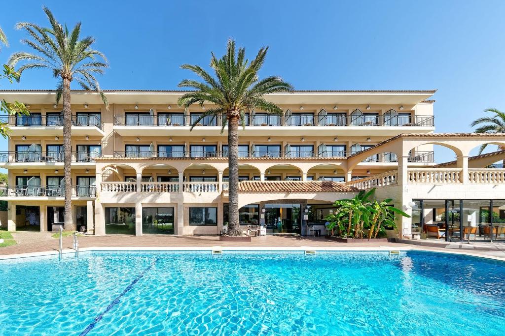 a hotel with a large swimming pool in front of a building at R2 Lago Playa Park in Cala Ratjada
