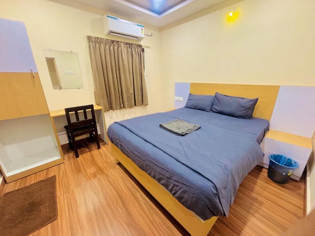 a bedroom with a blue bed and a chair at RI Krishna Residency in Visakhapatnam