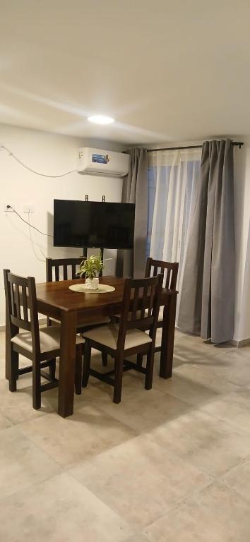 a wooden table with two chairs and a table with flowers on it at Dpto Amoblado in Villa María