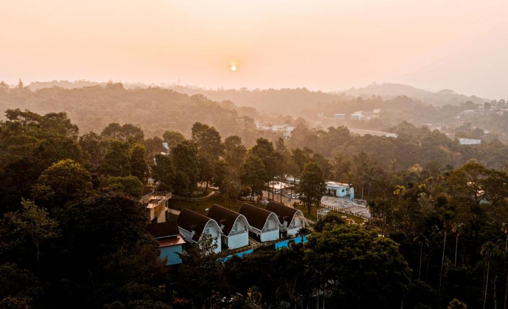 Blick auf ein Haus mit Bäumen und der Sonne am Himmel in der Unterkunft Golf Valley Luxury Resort Wayanad in Vythiri