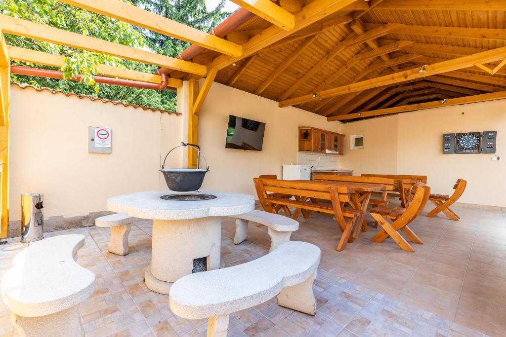 een patio met een tafel en banken en een houten plafond bij Zama Apartman in Hajdúszoboszló