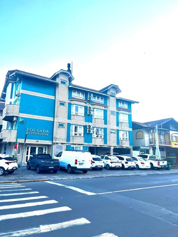 a blue building with cars parked in a parking lot at Pousada Ruppenthal in Canela