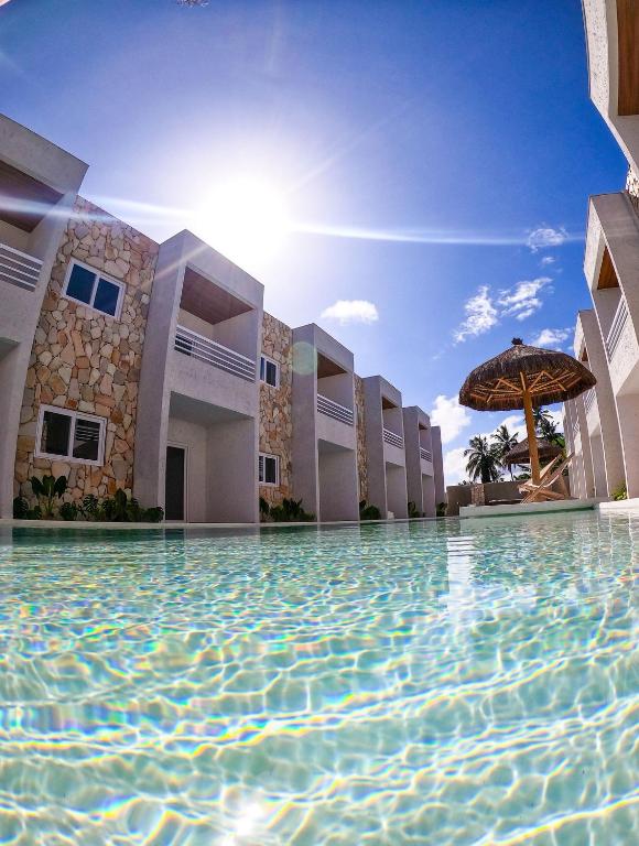 a swimming pool in front of a building with an umbrella at MHV Milagres - Curimã B 1 in Passo de Camarajibe