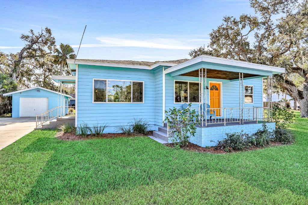 een blauw huis met een oranje deur in een tuin bij Edgewater- River Cottage in Edgewater