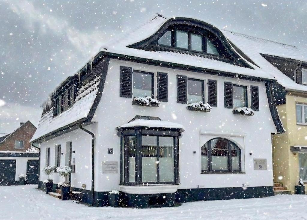 een wit huis bedekt met sneeuw in een tuin bij Ferienwohnung am Glockensee in Bad Laer
