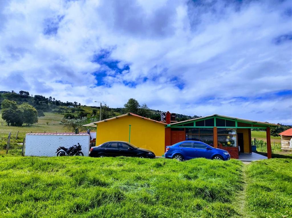 two cars parked in front of a yellow house at Casa de Campo San Cayetano de los vientos in Tibasosa