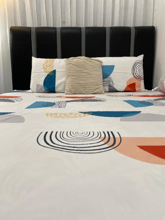 a bed with a black and white comforter on it at Cozy Homes BnB in Prampuan