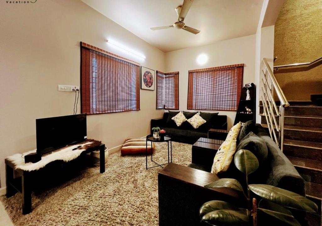 een woonkamer met een bank en een trap bij Eden Green Nest in Bangalore