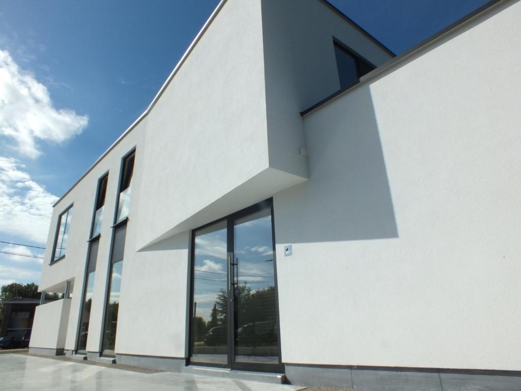 um edifício branco com grandes janelas do lado em B&B Vita Roka met extra Luxe Privé Wellness em Ursel
