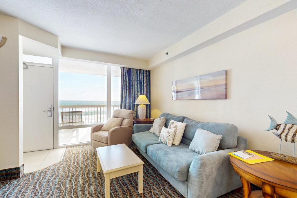 a living room with a blue couch and a balcony at Daytona Beach Resort 533- Oceanfront Oasis in Daytona Beach