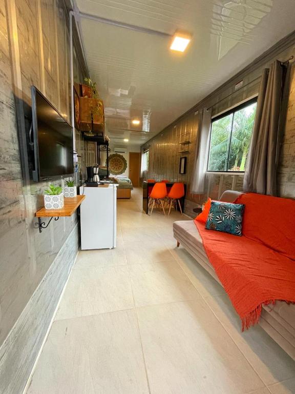 a living room with a couch and a tv at Estudio Praia do Estaleiro - Balneário Camboriú in Balneário Camboriú