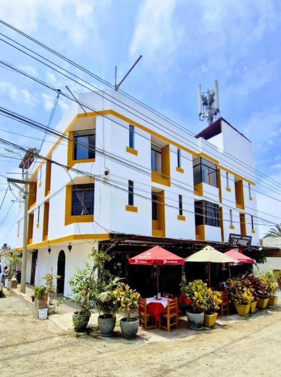 a yellow and white building with tables and umbrellas at Hostal Pulpos in Bombiso