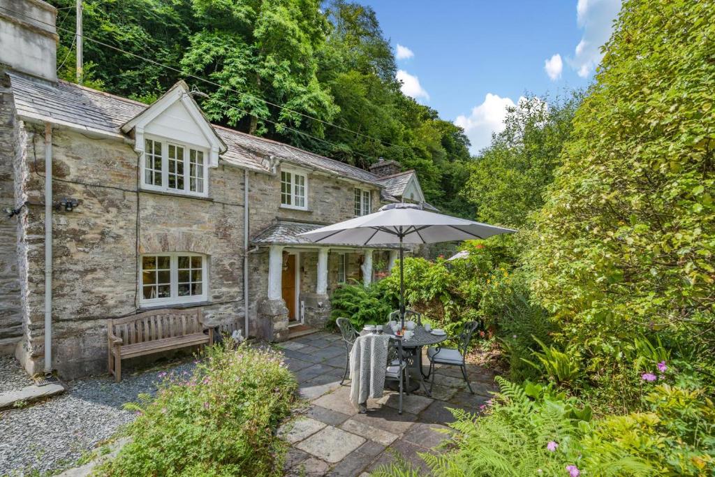 an old stone cottage with an umbrella and a table at 2 Bed in Looe oc-l30015 in Lansallos