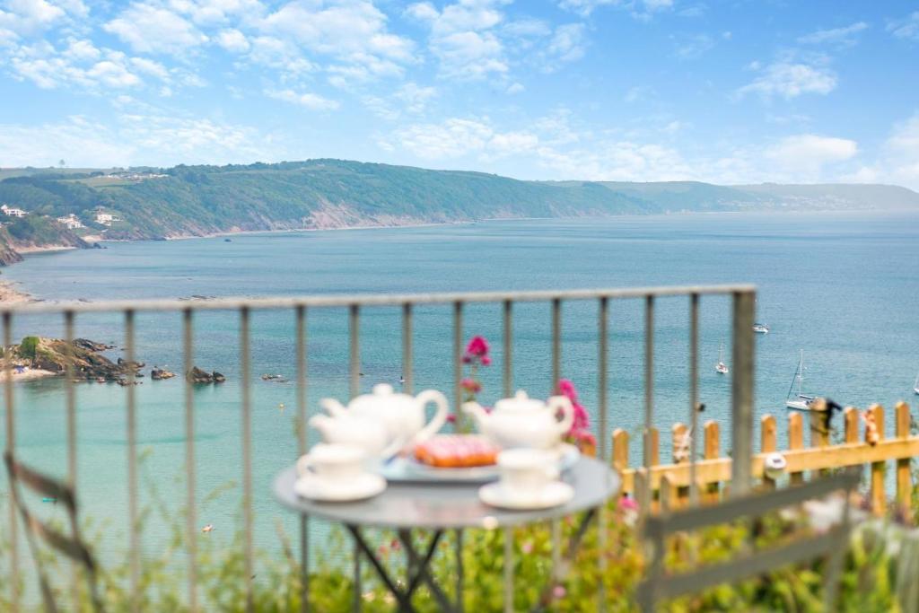 a table with two tea sets on a balcony overlooking the ocean at 2 Bed in Looe oc-l30026 in Looe