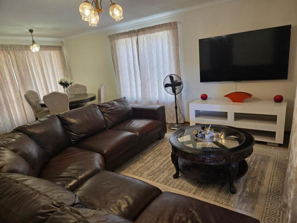 a living room with a leather couch and a coffee table at Hillcrest Cosy Cottage in Hillcrest