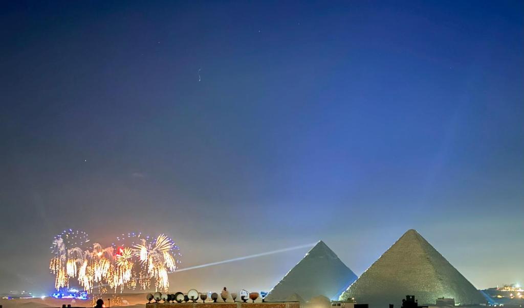 een groep mensen die met vuurwerk rond de piramides staan bij Five Pyramids View in Caïro
