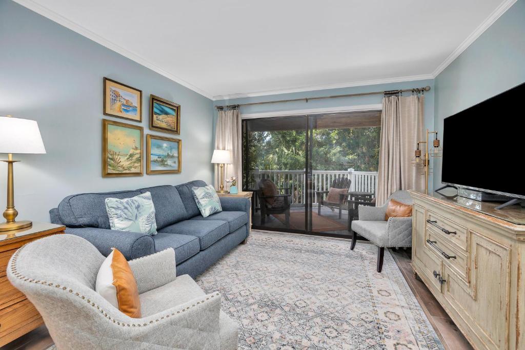 a living room with a blue couch and a tv at Shipwatch #106 in East End