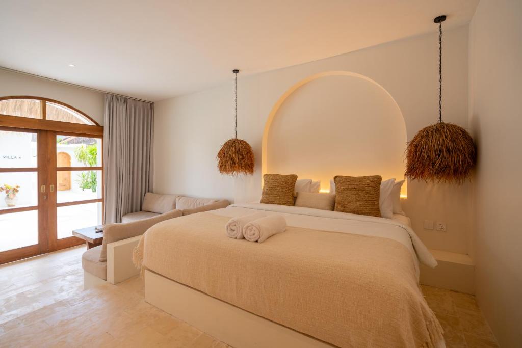 een slaapkamer met een groot bed en een bank bij Luna Kai Villas in Uluwatu
