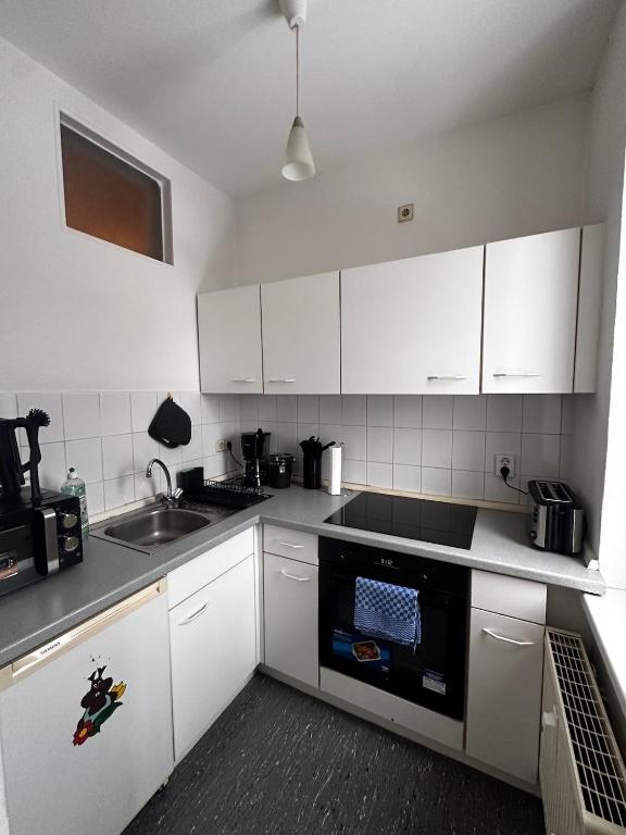 2-Zi-Wohnung und Parkplatz für Geschäftsreisende في رودرسدورف: مطبخ بخزائن بيضاء ومغسلة