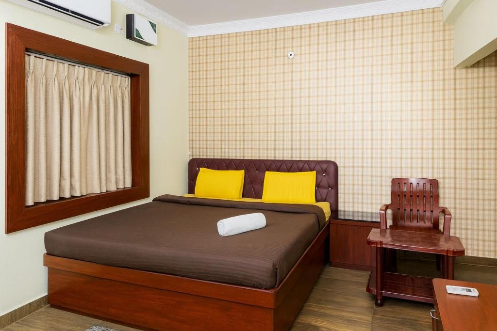 ein Schlafzimmer mit einem Bett mit gelben Kissen und einem Stuhl in der Unterkunft Vensa corporate Inn in Bhubaneshwar