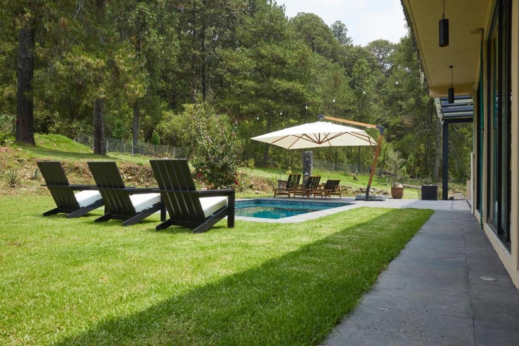 Dos sillas y una sombrilla junto a una piscina. en La Malenita casa en Amanalco, en Amanalco de Becerra