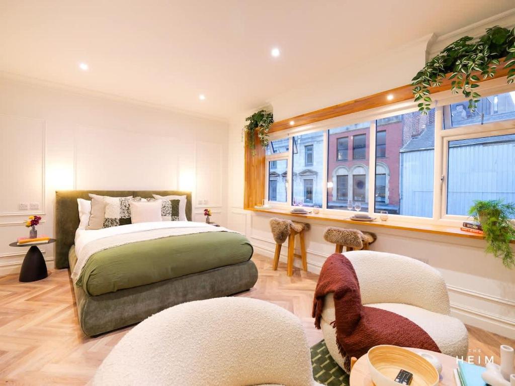 a bedroom with a bed and two chairs and a window at Ember at The Heim Residences in Manchester