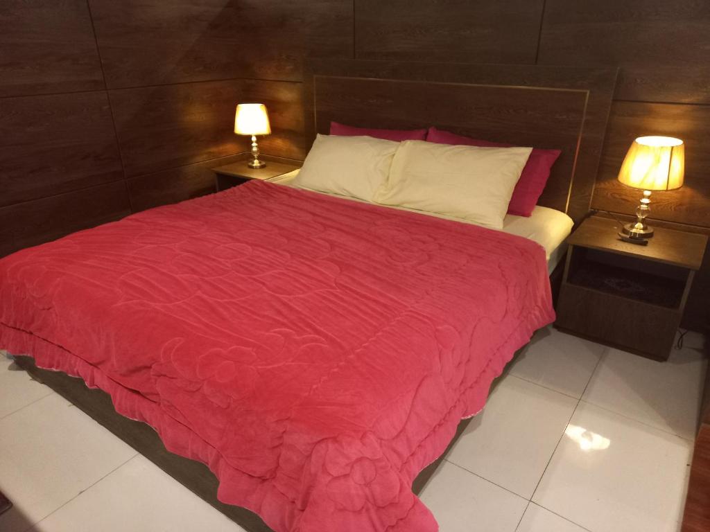 ein Schlafzimmer mit einem großen roten Bett mit zwei Lampen in der Unterkunft Executive Studio Apartment Lahore in Lahore