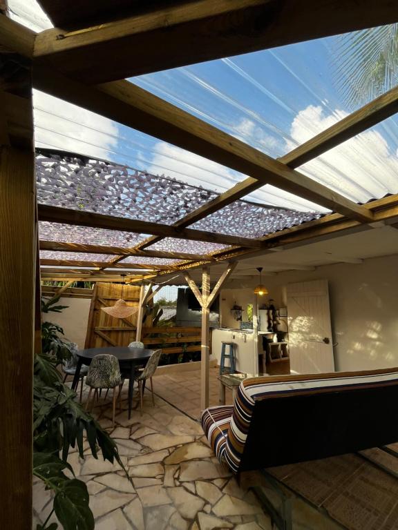 een patio met een dak met een tafel en stoelen bij Caraiba - Maisons de Vacance avec Piscine et Toit Terrasse in Sainte-Anne