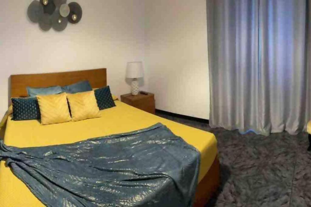 een slaapkamer met een groot bed met een geel dekbed bij Alvarenga House in Maia