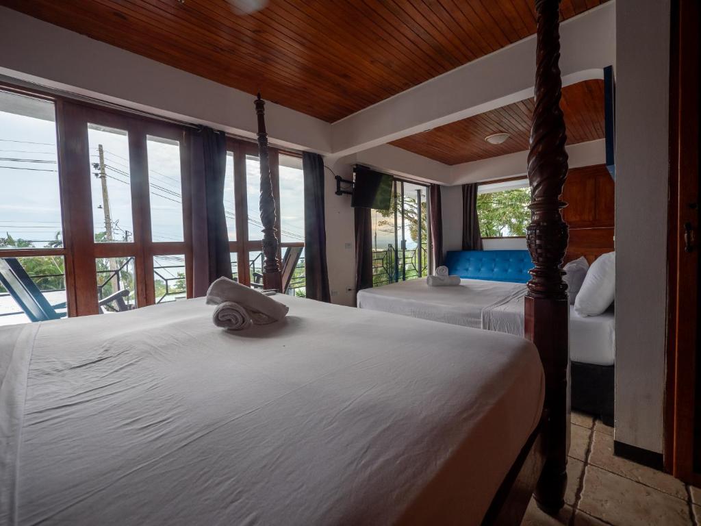 a bedroom with two beds in a room with windows at Hotel Manuel Antonio Inn in Quepos