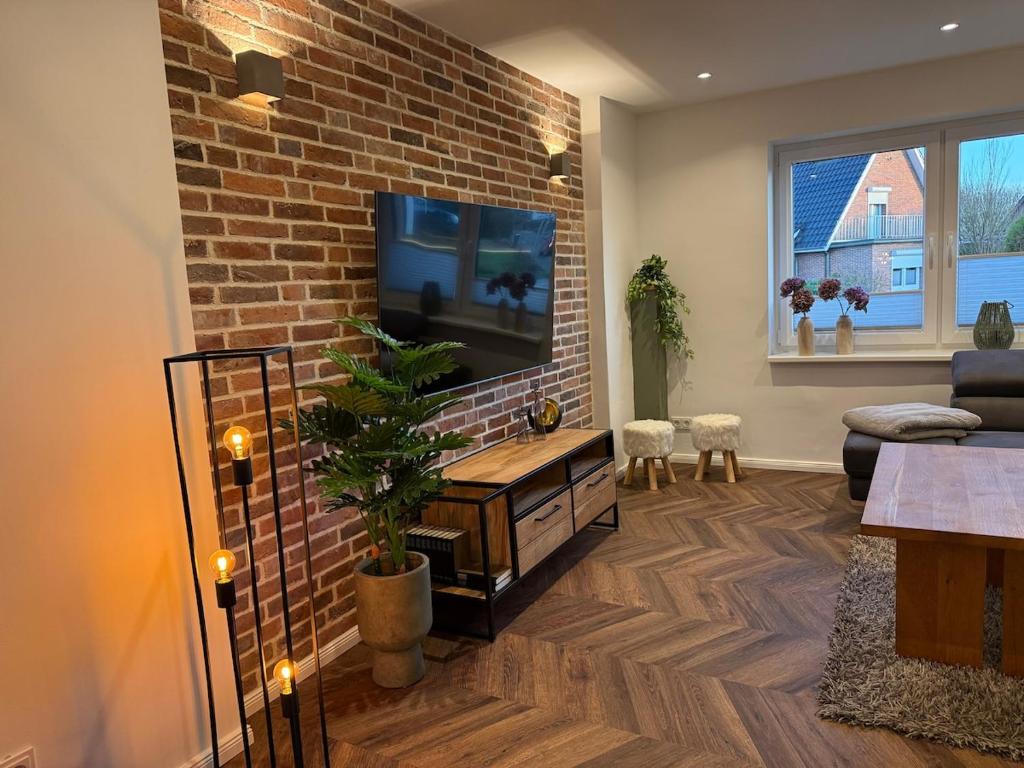 a living room with a brick wall and a flat screen tv at Fewo Voßbarg ünnen in Rastede