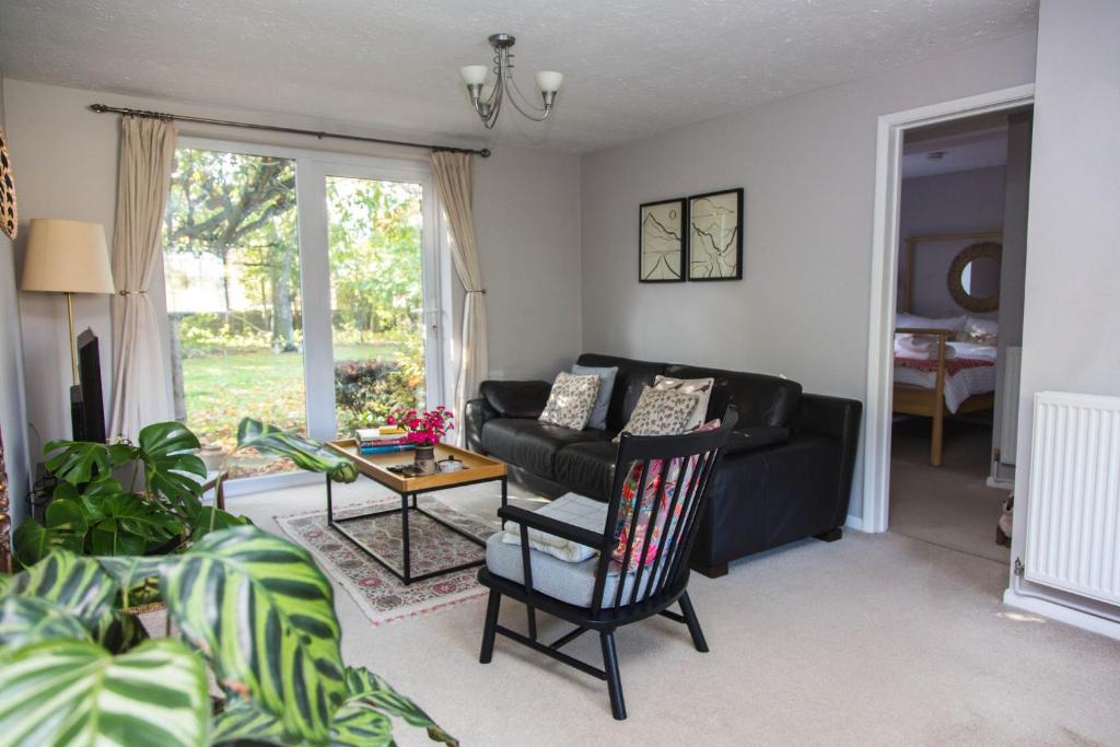 ein Wohnzimmer mit einer schwarzen Couch und einem Tisch in der Unterkunft Calm Private Apartment in Ashford Ideal to Work, Rest Explore in Smeeth