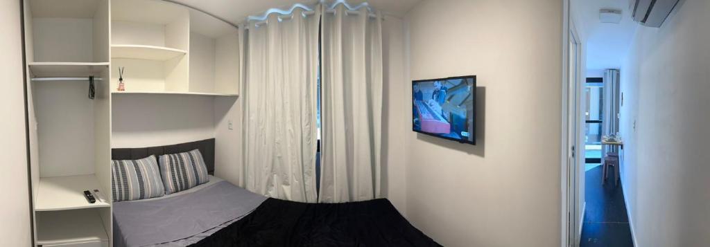 een kleine slaapkamer met een bed en een spiegel bij Box 07 a 950 mt do mar, ar- condicionado, TV smart, cozinha privativa in Itapema