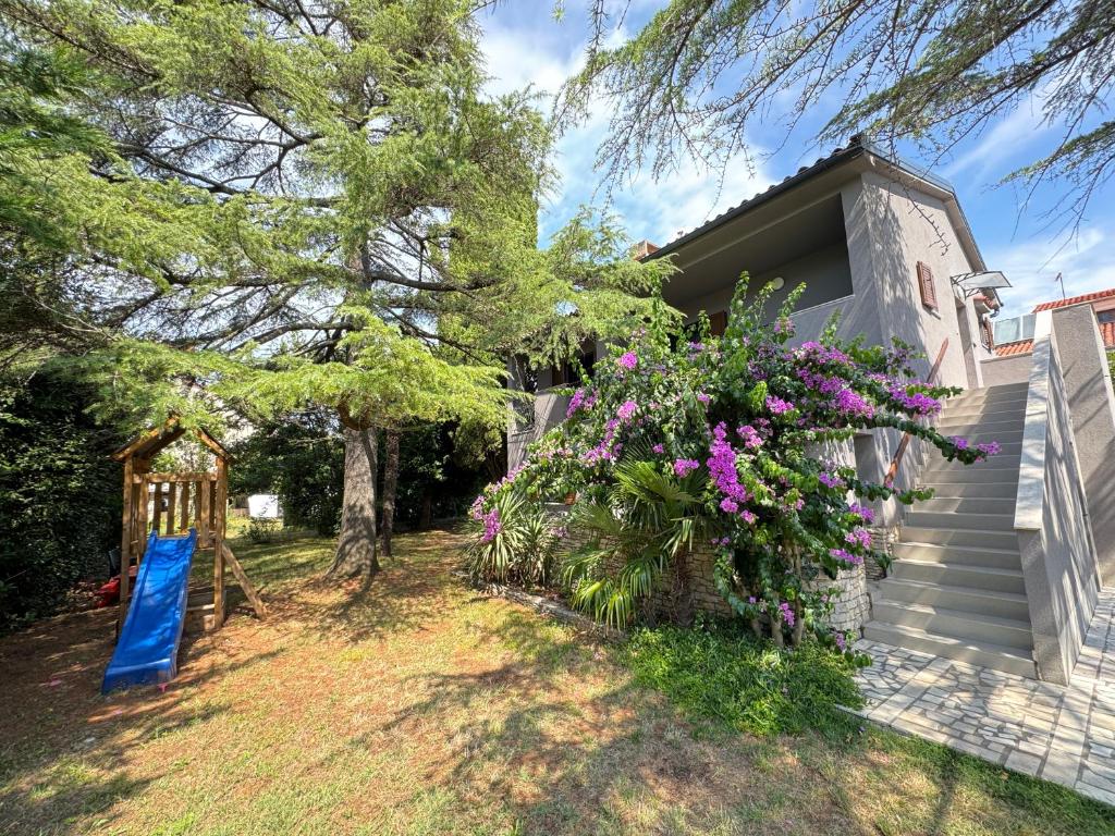 Una casa con flores púrpuras a un lado. en Flowers Apartments Medulin, Fucane 2, en Medulin