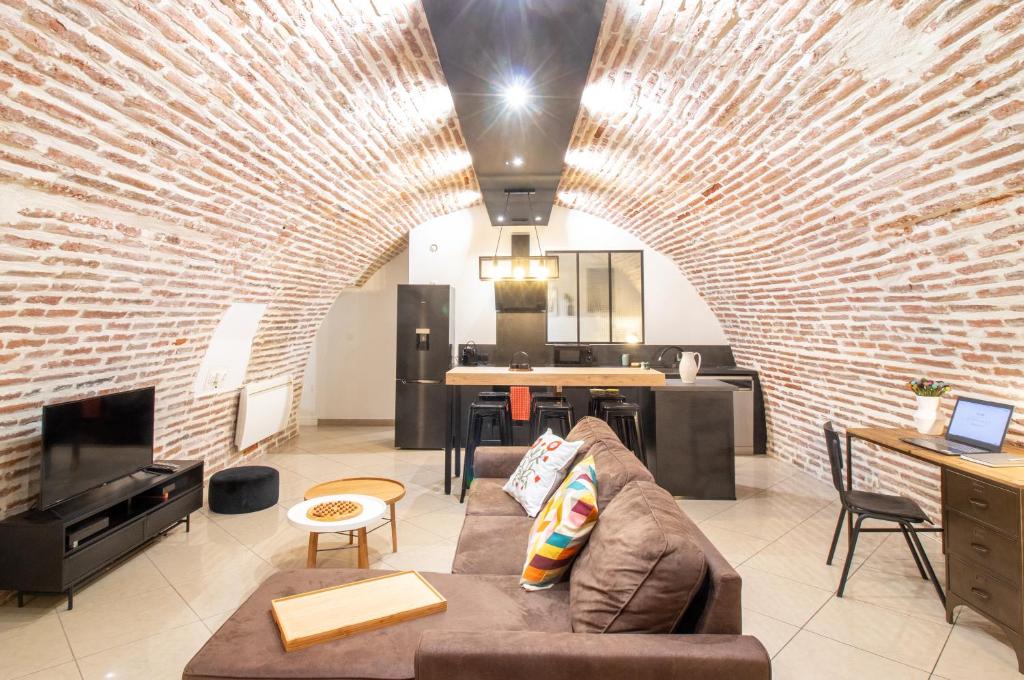 ein Wohnzimmer mit einer Couch und einer Ziegelwand in der Unterkunft Le Rinaldi Loft in Albi