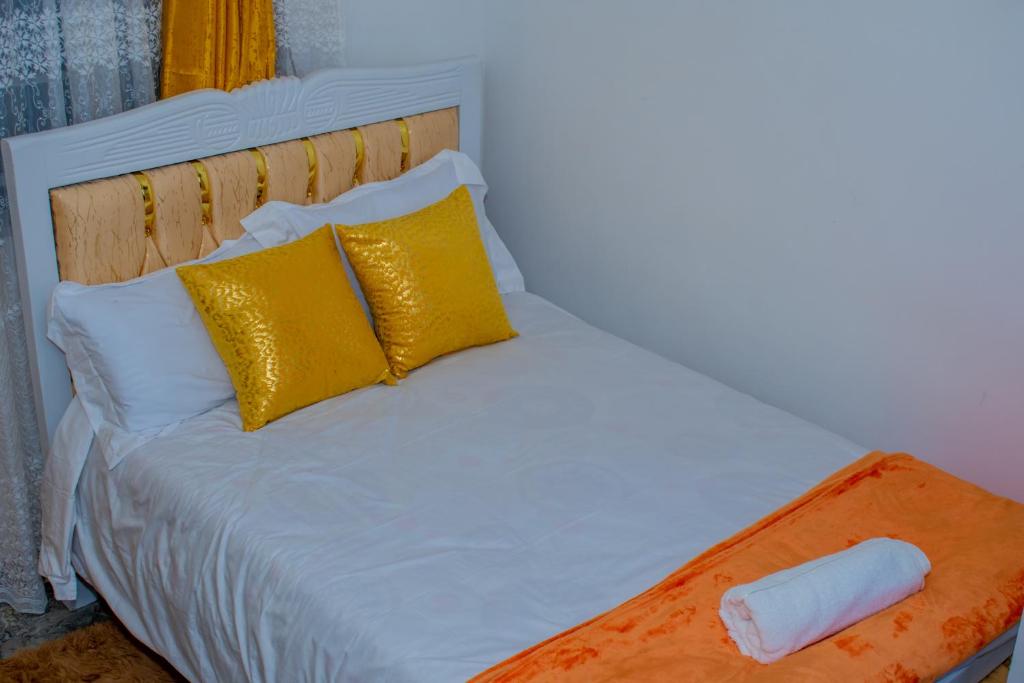 a white bed with gold pillows at Delsystays in Ruaka